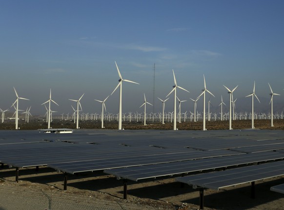 epa06086174 Wind turbine generators stand near a solar array in the San Gorgonio Mountain Pass in the San Bernardino Mountains near Palm Springs, California, USA, 13 July 2017. More than 4,000 wind tu ...