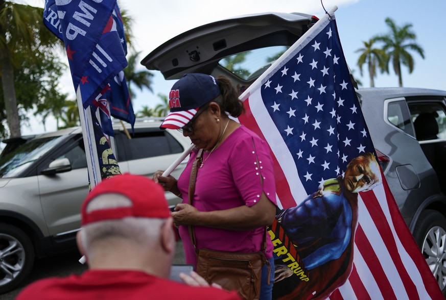 A woman holds a flag depicting former President Donald Trump as a superhero as Trump supporters gather at Tropical Park in Miami, Sunday, June 11, 2023, to drive in convoy to Trump&#039;s Mar-a-Lago c ...