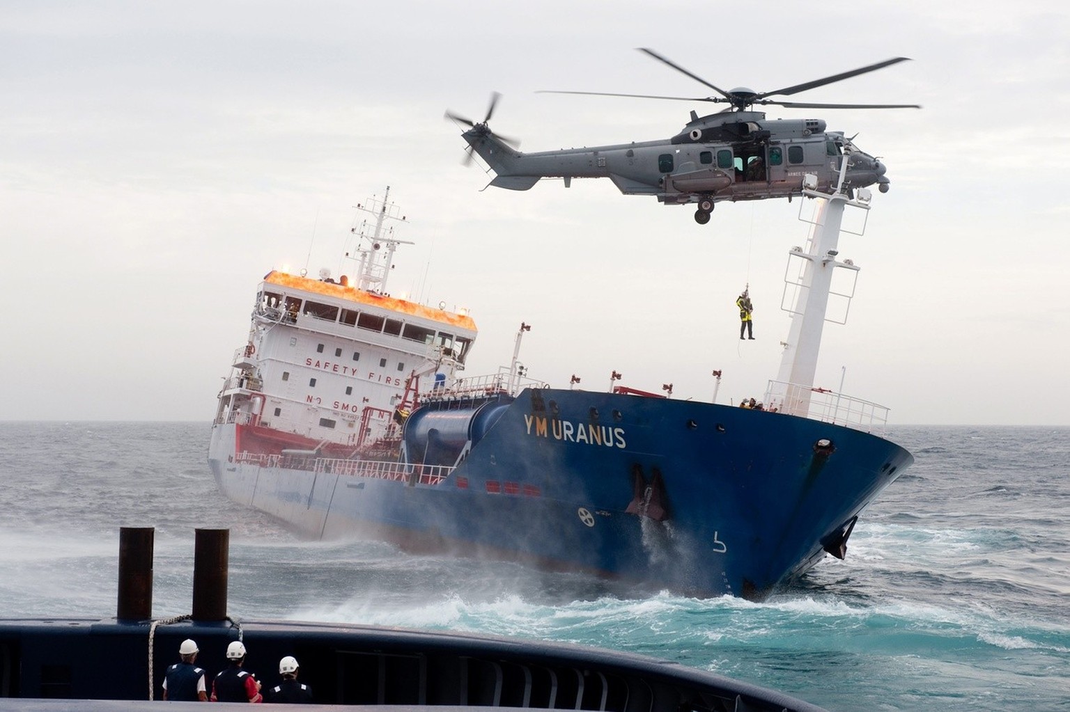 epa02383526 Handout photo issued by the French Navy in Brest, France, 08 October 2010, showing a rescue helicopter hovering over the YM Uranus, that is heavily listing after having collided with anoth ...