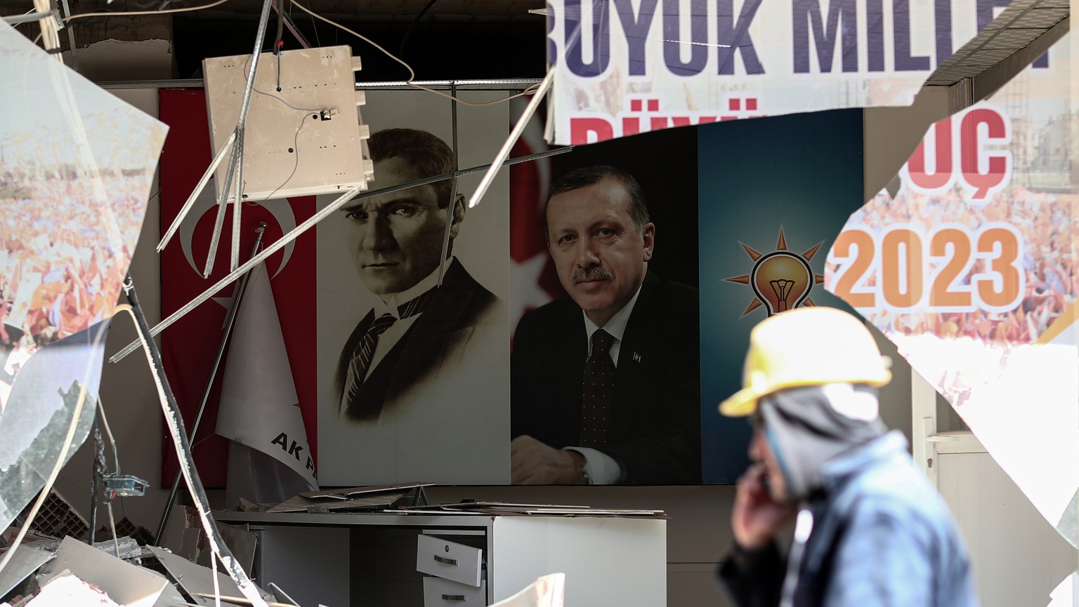 epa10465210 A person walks in front of portraits depicting Mustafa Kemal Ataturk, founder of modern Turkey (L), and Turkey&#039;s President Recep Tayyip Erdogan (R) at the site of a collapsed building ...