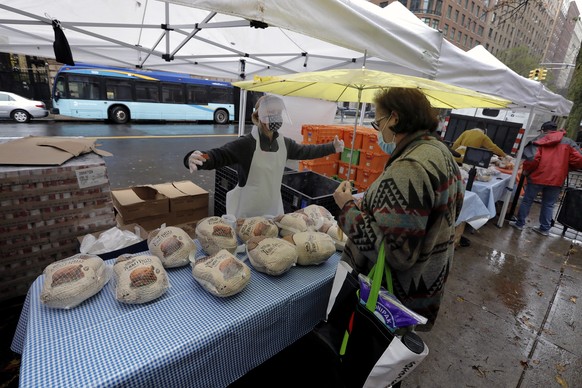 epa08818805 A person receives a turkey from the West Side Campaign Against Hunger at St. Paul &amp; St. Andrew United Methodist Church on West 86th Street in New York, New York, USA, 13 November 2020. ...