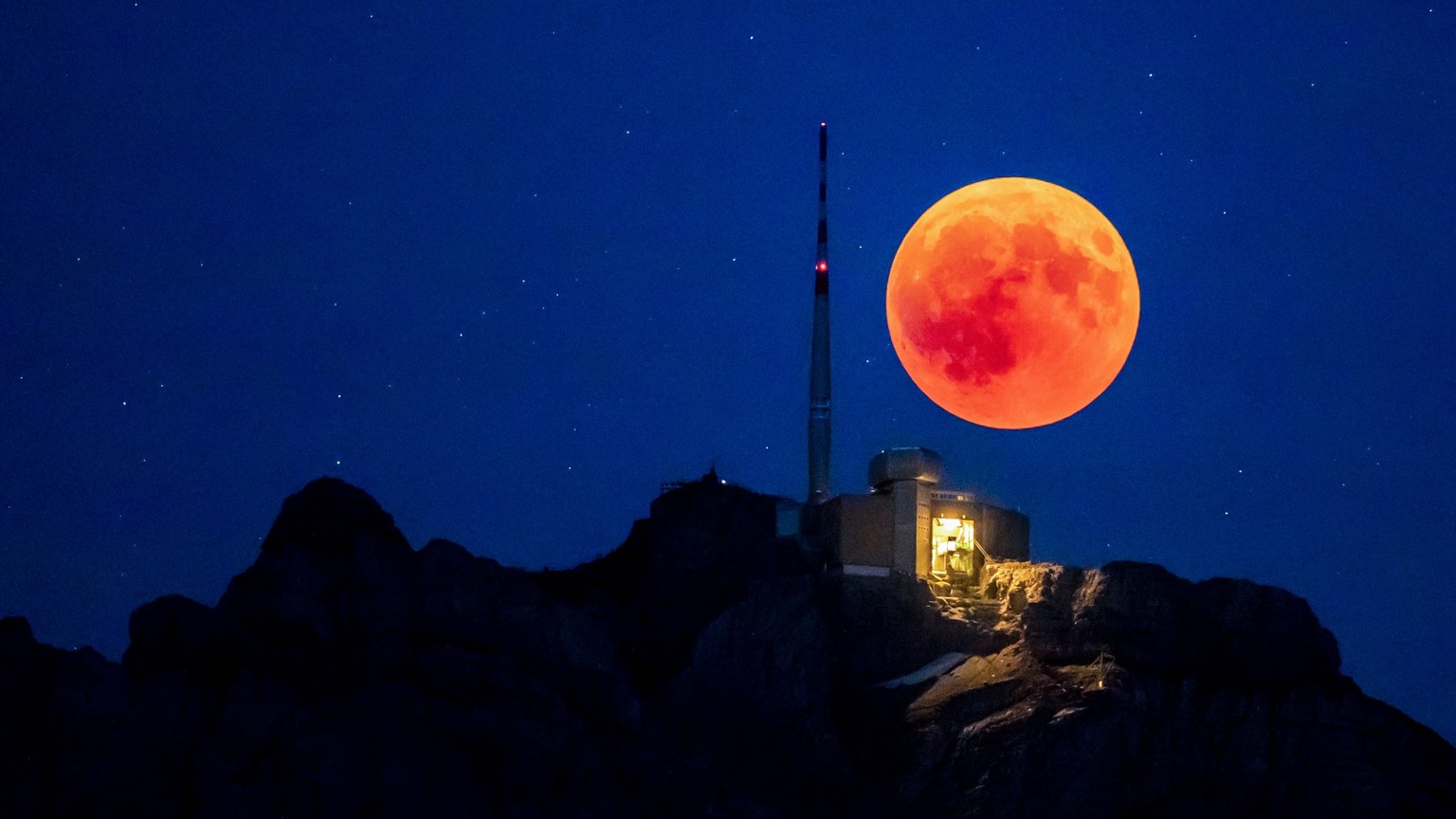 The blood moon rises behind the Saentis (2502m, Alpstein, Canton of Appenzell) on the night of the longest total lunar eclipse of the 21st century. (KEYSTONE/Christian Merz)