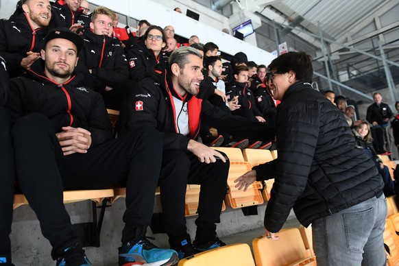 Switzerland's national soccer players Haris Seferovic, left, and Valon Behrami, center, shake hands with HC Lugano President Vicky Mantegazza, right, before the preliminary round game of National ...