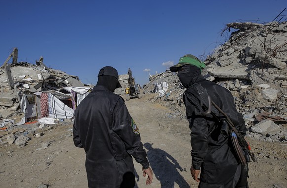 epa12562252 Fighters of the Al-Qassam Brigades, the military wing of the Hamas movement, stand guard as they search for the bodies of Israeli hostages alongside Red Cross workers in Jabaliya refugee c ...