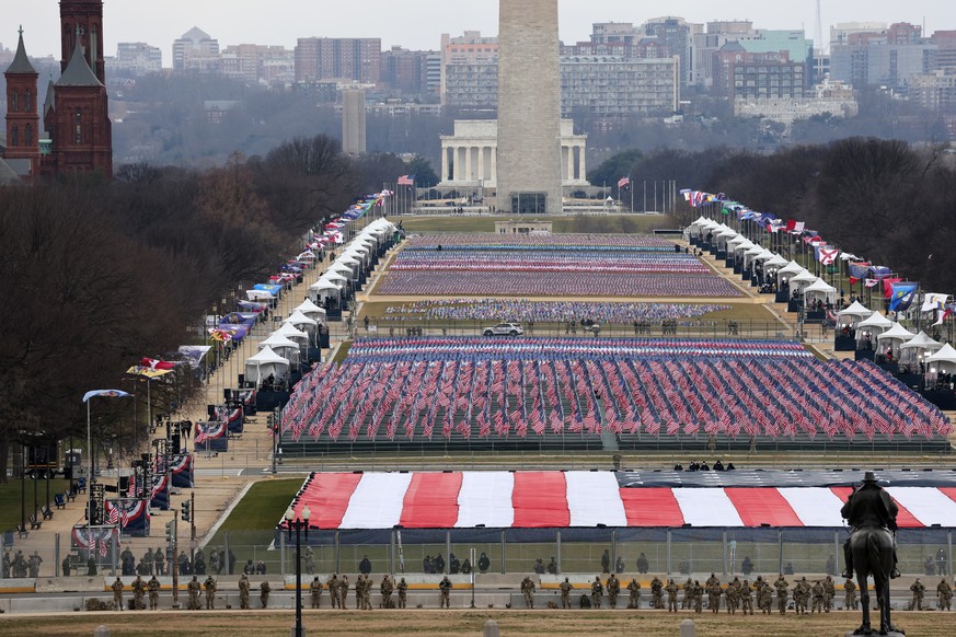 epa08952940 Members of the National Guard look on as American flags decorate the Field of Flags at the National Mall during the inauguration of Joe Biden as US President in Washington, DC, USA, 20 Jan ...