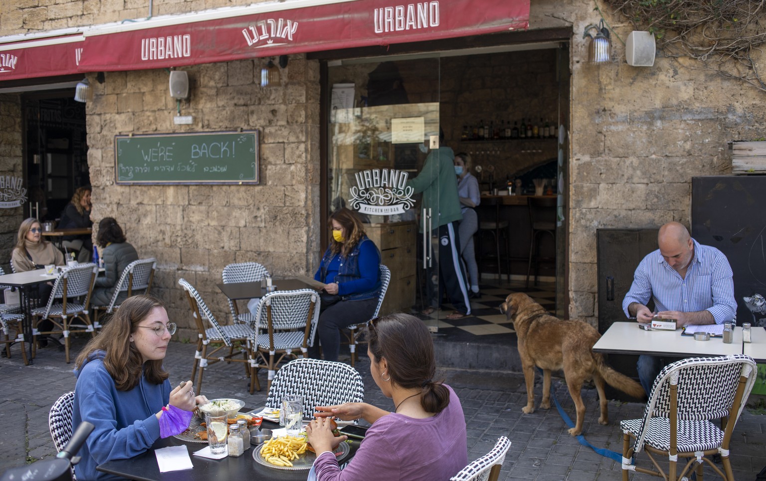 People eat in a restaurant as restrictions are eased following months of government-imposed shutdowns, in Tel Aviv, Israel, Sunday, March 7, 2021. Israel reopened most of its economy Sunday as part of ...