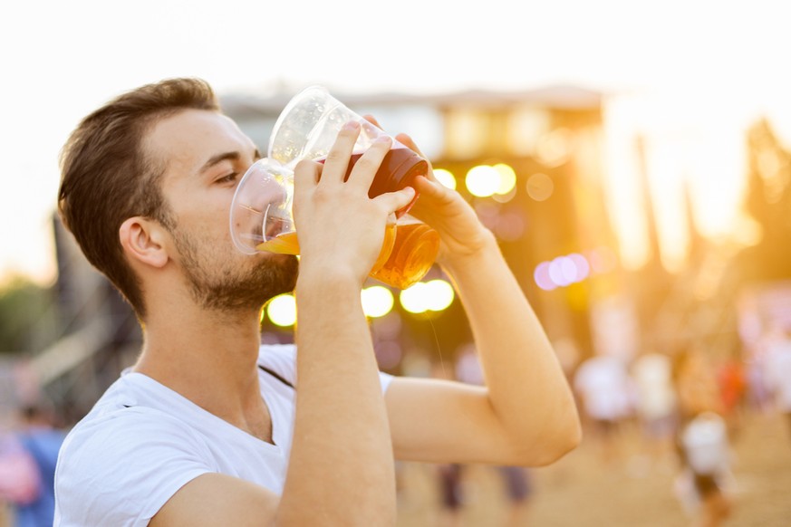 Mann trinkt mehrere Becher Bier gleichzeitig