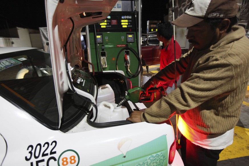 A taxi driver fills containers in his trunk with gasoline after waiting for hours at a fuel station in Valle de Bravo, Mexico, late Friday, Dec. 30, 2016. Most of the city&#039;s fill-up stations were ...