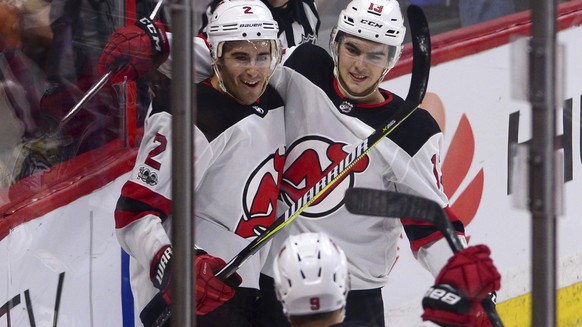 New Jersey Devils defencsman John Moore, left, celebrates his game winning goal against the Ottawa Senators with teammates Nico Hischier, right, and Taylor Hall in overtime in an NHL hockey game, Thur ...