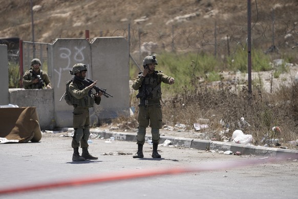 Israeli soldiers work at the site of an alleged car-ramming attack near Beit Hagai, a Jewish settlement in the hills south of the large Palestinian city of Hebron, Wednesday, Aug. 30, 2023. The Israel ...