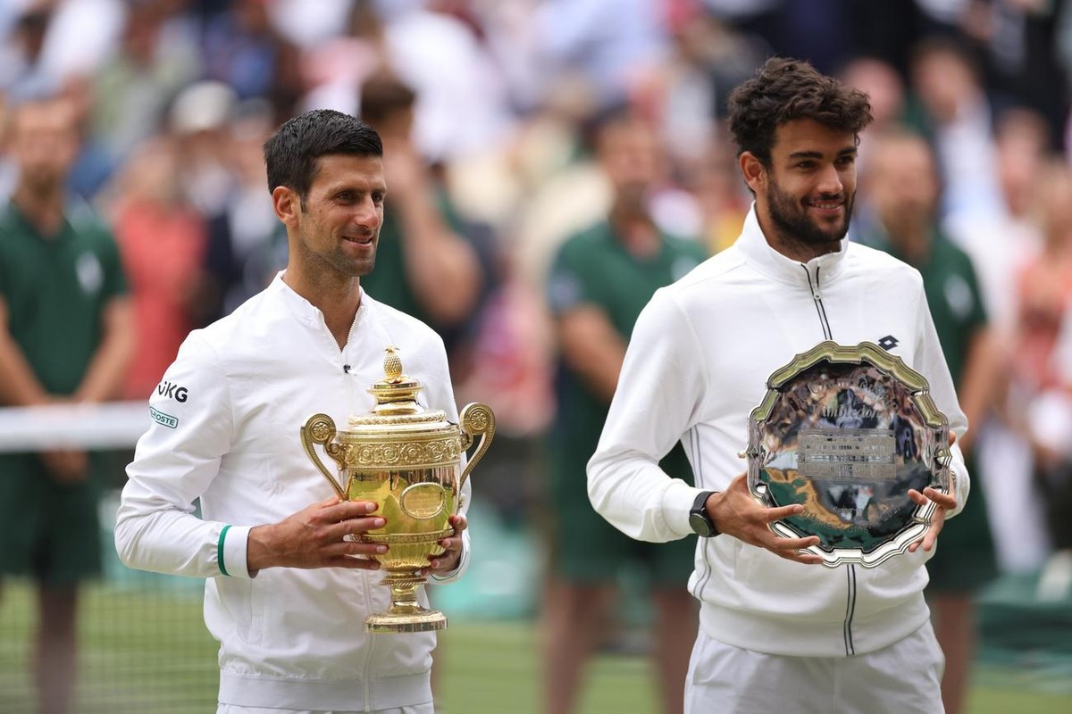 epa09338003 Novak Djokovic (L) of Serbia poses for a photo with the trophy after winning the men's final against Matteo Berrettini (R) of Italy at the Wimbledon Championships, Wimbledon, Britain  ...