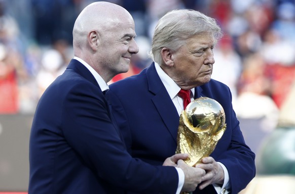 epa13122000 FIFA President Gianni Infantino (L) and US President Donald J. Trump carry the World Cup Trophy to the podium during the awards ceremony after the FIFA World Cup 2026 final match Spain aga ...