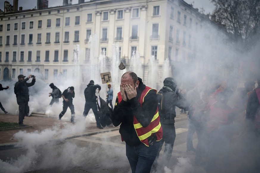 Protesters run amid the tear gas during a demonstration in Lyon, central France, Thursday, March 23, 2023. French unions are holding their first mass demonstrations Thursday since President Emmanuel M ...