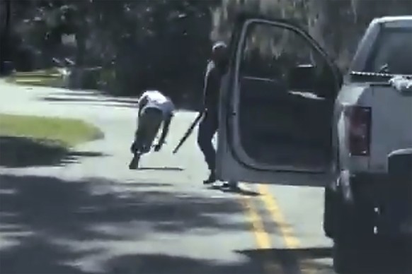 In this image from video posted on Twitter Tuesday, May 5, 2020, Ahmaud Arbery stumbles and falls to the ground after being shot as Travis McMichael stands by holding a shotgun in a neighborhood outsi ...