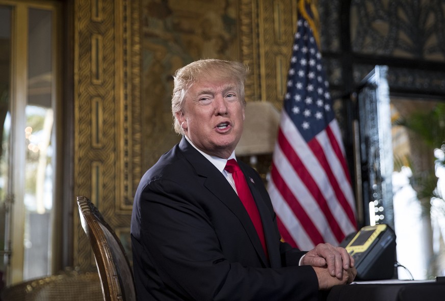 President Donald Trump turns to talk to the gathered media during a Christmas Eve video teleconference with members of the mIlitary at his Mar-a-Lago estate in Palm Beach, Fla., Sunday, Dec. 24, 2017. ...