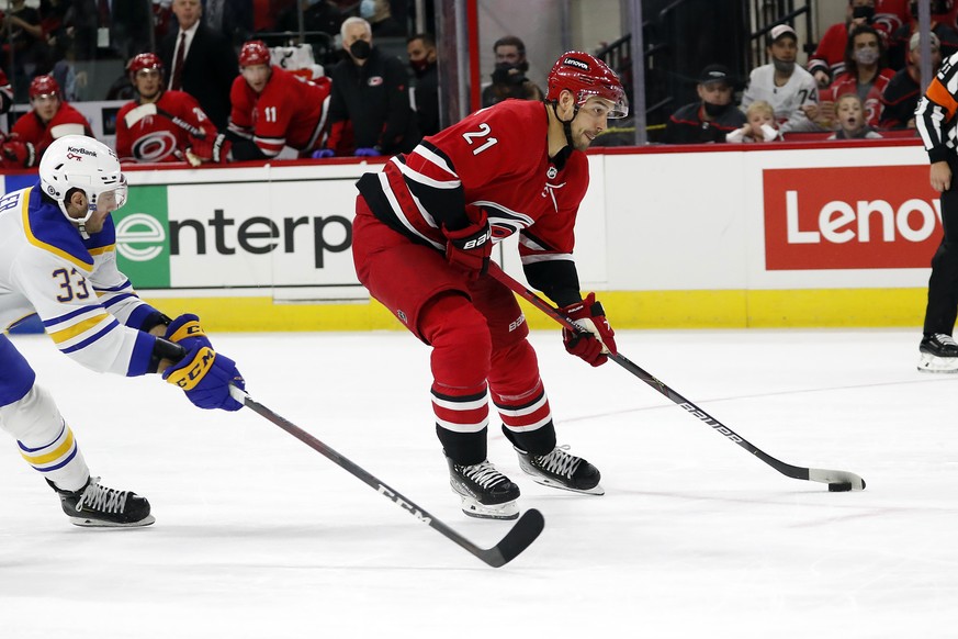 Carolina Hurricanes&#039; Nino Niederreiter (21) skates the puck away from Buffalo Sabres&#039; Colin Miller (33) to score a goal during the second period of an NHL hockey game in Raleigh, N.C., Satur ...