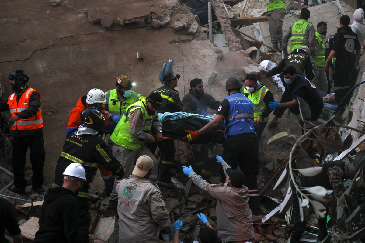 epa12875770 First responders carry the body of a victim amid the rubble of a partially destroyed residential building following an Israeli air strike, in the Tallet al-Khayat neighborhood of Beirut, L ...