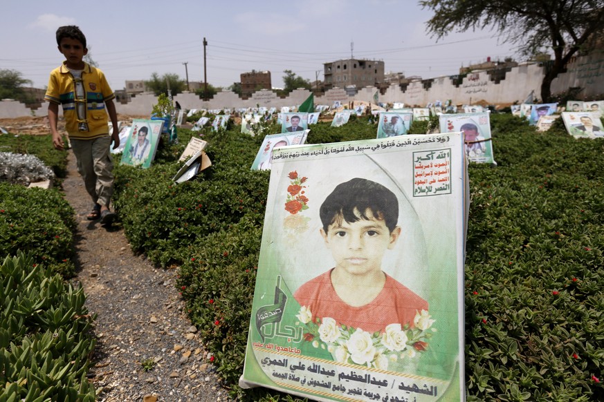 epa06131961 A Yemeni boy walks past the grave with a portrait of a late child allegedly killed in the ongoing conflict, at a cemetery in Sanaa, Yemen, 08 August 2017. According to UNICEF recent repor ...
