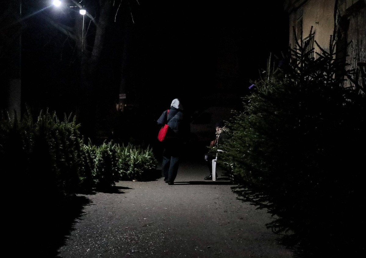 December 13, 2025, Odessa, Ukraine: A woman walks along dark Konnaya Street among Christmas trees for sale. As a result of the massive combined attack on Odeshchina, on December 13, 2025, energy infra ...