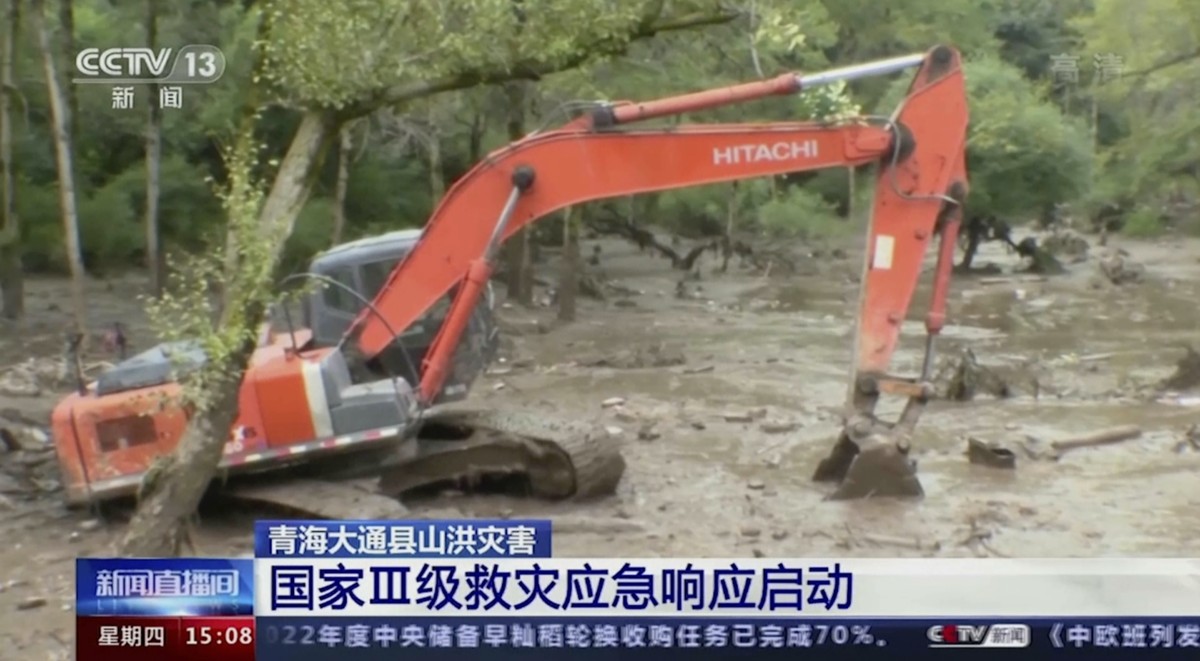 In this image taken from video footage run by China's CCTV, an excavator tries to clear mud from an area in the aftermath of flooding in Datong county in western China's Qinghai province on  ...