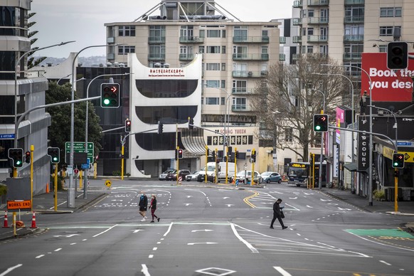 People cross nearly empty streets in the central business district of Auckland, New Zealand, Friday Aug. 27, 2021. By early next week, New Zealanders should know if their government&#039;s strict new  ...