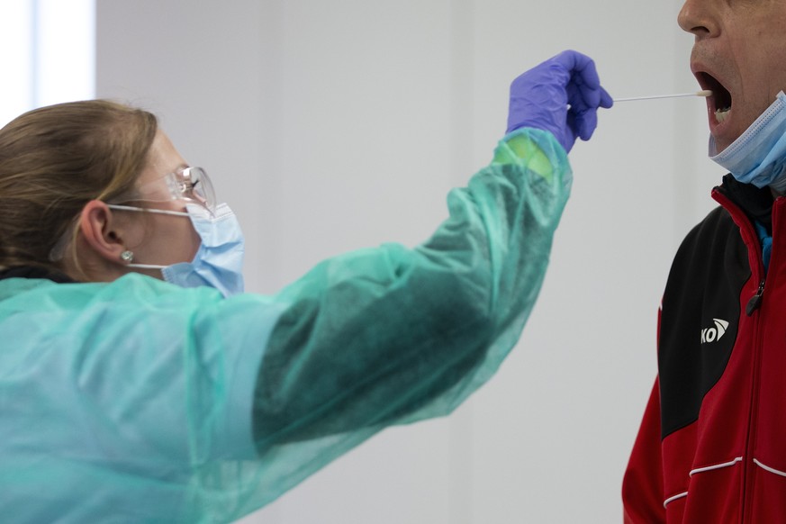 Eine Mitarbeiterin des Testcenters macht einen Abstrich bei einem Mann, beim mobilen Coronavirus Testcenter im BEA Gelaende, am Montag, 30. Maerz 2020 in Bern. Das Testcenter steht seit Montagnachmitt ...