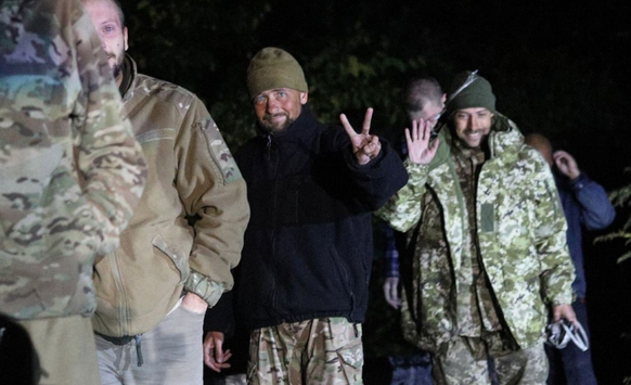 Freigelassene Soldaten winken nach ihrer Ankunft in der Ukraine in die Kamera.