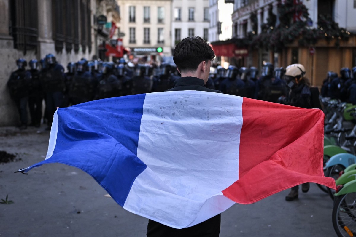 epa13290102 A protester holds the France national flag as clashes with riot police erupt at Bastille square during a demonstration over school conditions in Paris, France, 08 October 2026. A wave of n ...