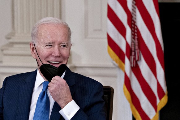 epa09741932 US President Joe Biden pulls down his protective mask to speak while meeting with chief executive officers of electric utilities companies, in the State Dining Room of the White House in W ...