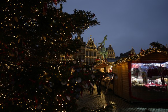 People walk past a tree and decorated guild houses at a Christmas market in the center of Antwerp, Belgium, Monday, Dec. 18, 2023. (AP Photo/Virginia Mayo)