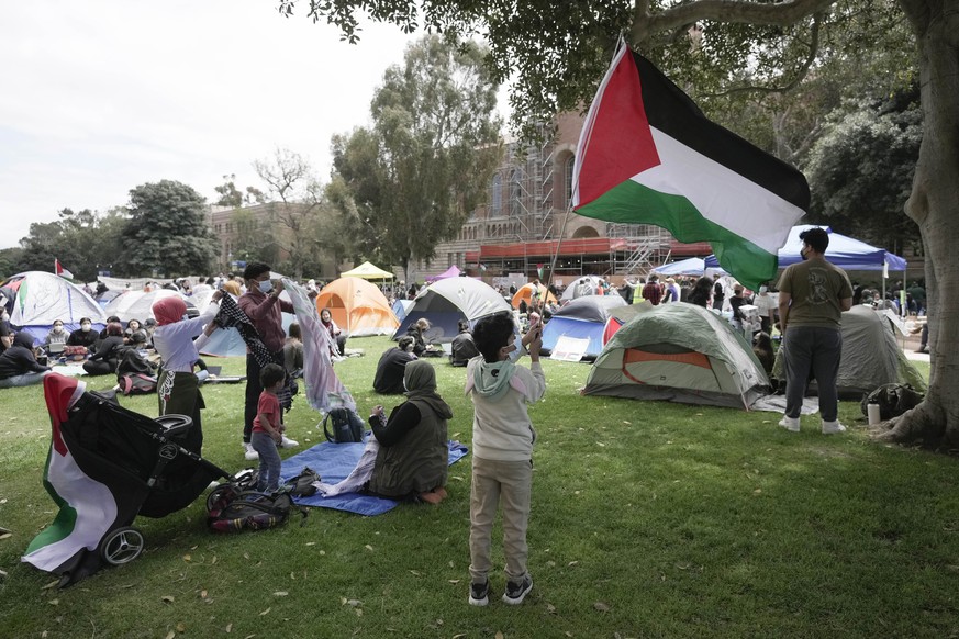 A boy waves a Palestinian flag at an encampment on the University of California, Los Angeles (UCLA) campus Thursday, April 25, 2024, in Los Angeles. (AP Photo/Jae C. Hong)