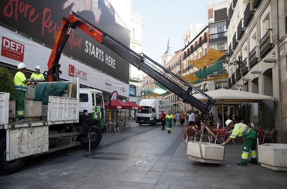 epa06149592 Local workers place heavy flower beds in Carmen street to block the avenue and avoid the vehicular traffic in downtown Madrid, Spain, 18 August 2017, a day after the terrorist attacks in C ...