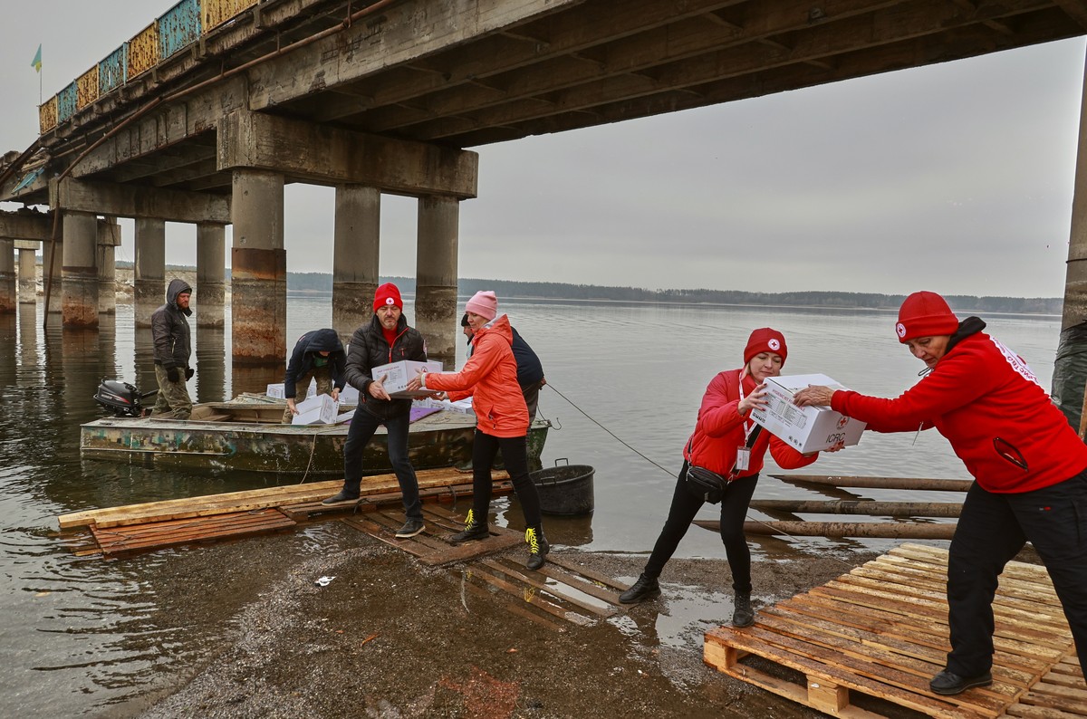 epa10296690 Red Cross workers move medical supplies by boat across a reservoir next to a bridge that was destroyed by shelling in the settlement of Staryi Saltiv, Kharkiv region, Ukraine, 09 November  ...