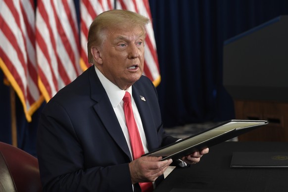 FILE - In this Saturday, Aug. 8, 2020, file photo, President Donald Trump prepares to sign four executive orders during a news conference at the Trump National Golf Club in Bedminster, N.J. As employe ...