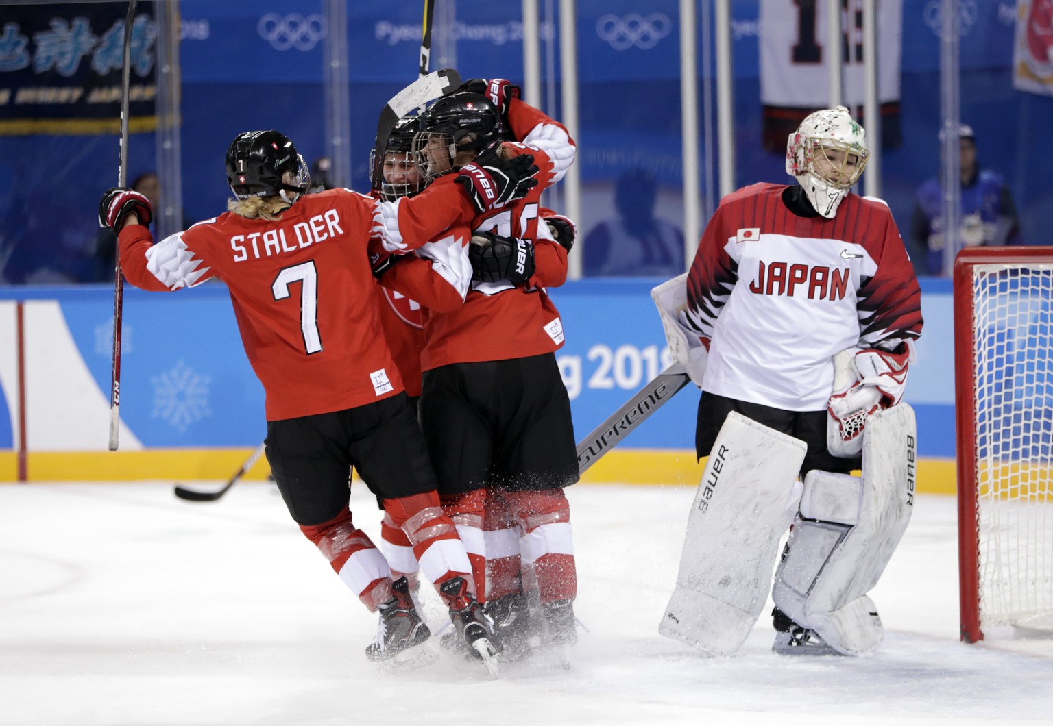 Sara Benz, second from left, of Switzerland, celebrates a goal with her teammates as Nana Fujimoto (1), of Japan, skates off during the second period of the preliminary round of the women&#039;s hocke ...