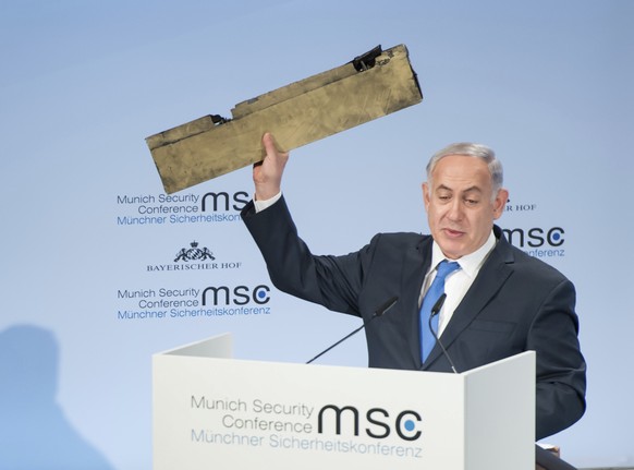 In this photo released by Lennart Preiss/MSC 2018, Israeli Prime Minister Benjamin Netanyahu, holds a part of a downed drone during his speech at the Munich Security Conference, MSC, in Munich , Germa ...