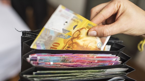 ZUM THEMA GELD STELLEN WIR IHNEN HEUTE, DONNERSTAG, 1. OKTOBER 2015, FOLGENDES NEUES BILDMATERIAL ZUR VERFUEGUNG --- A waitress takes a one ten Swiss franc bill out of a her wallet, photographed in Zu ...