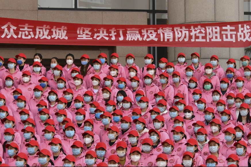 In this photo released by Xinhua News Agency, medical workers gather near a banner which reads &quot;Unite as one, resolutely win the battle against epidemic prevention and control&quot; during a depa ...