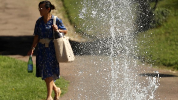 epa10813392 A woman walks with a bottle of water in a local garden in Valence, Southern France, 22 August 2023. Four departments, Drome, Ardeche, Rhone and Haute Loire, activated a red alert due to a  ...
