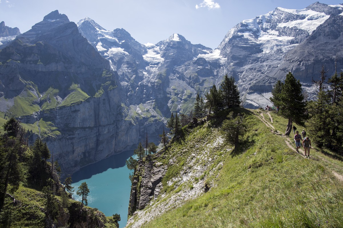 People walk around the lake of Oeschinen "Oeschinensee" (1578 meters above sea) and the mountains, above Kandersteg, in the Bernese Oberland, this Sunday, July 30, 2017. (KEYSTONE/Anthony An ...