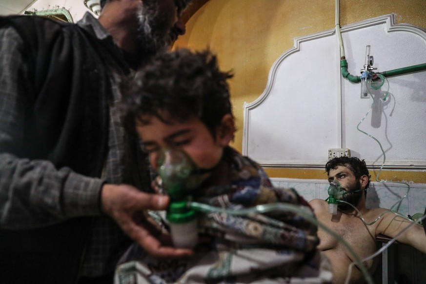 epa06565552 An affected child and man receive treatment after a gas attack on al-Shifunieh village, in Eastern Ghouta, Syria, 25 February 2018 (issued 26 February 2018). According to activists working ...