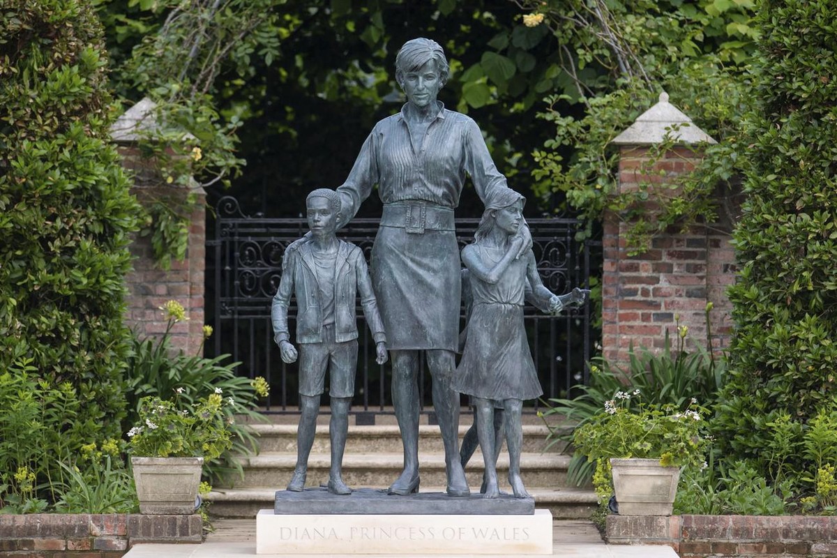 La statue en bronze représente la princesse aux cheveux courts, entourée de trois enfants, posant ses mains sur les épaules de deux d'entre eux.