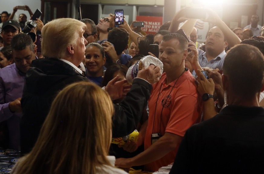 epa06243122 US President Donald Trump (L) gives kitchen paper in Guaynabo, San Juan, Puerto Rico, 03 October 2017. Trump arrives to Puerto Rico to evaluate the response to hurricane Maria on the islan ...