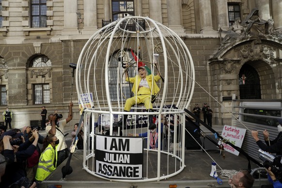 FILE - Fashion designer Vivienne Westwood sits suspended in a giant bird cage in protest against the extradition of WikiLeaks founder Julian Assange to the U.S., outside the Old Bailey court, in Londo ...