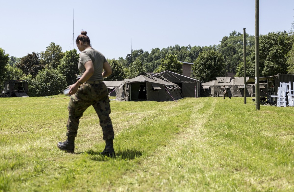 A female soldier walks over a meadow, pictured on site of the medical corps of the Swiss Armed Forces on June 18, 2013, in Buetschwil, canton of St. Gallen, Switzerland. A medical unit of the army run ...