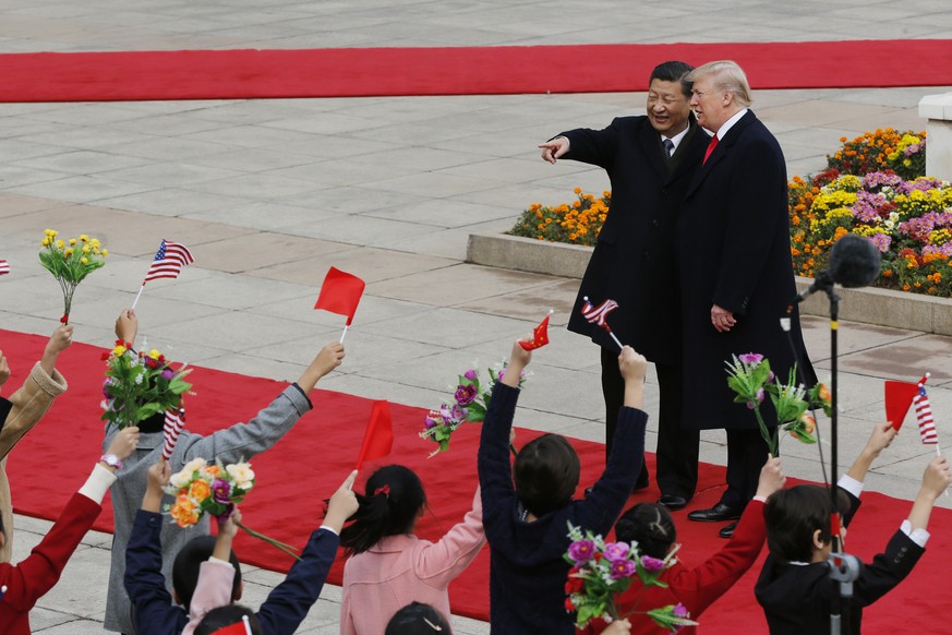 U.S. President Donald Trump, right, chats with Chinese President Xi Jinping as they are greeted by children waving flowers and flags during a welcome ceremony at the Great Hall of the People in Beijin ...