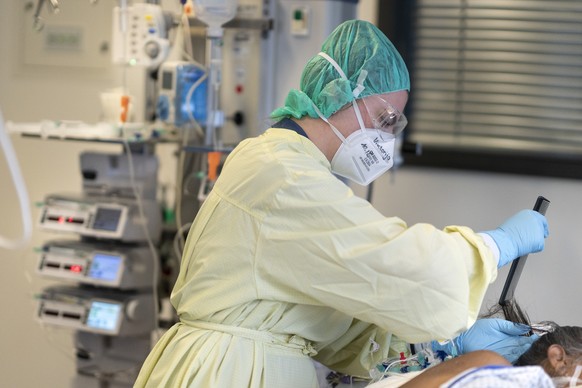 Eine Krankenschwester kaemmt einemCovid-Patientin die Haare auf der Covid-19-Intensivabteilung im Stadtspital Triemli am 10. Dezember 2020 in Zuerich. (KEYSTONE/Gaetan Bally)