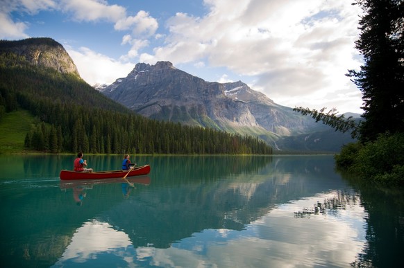 Couple canoeing on Emerald Lake with views of the mountains in Yoho National Park near Field.