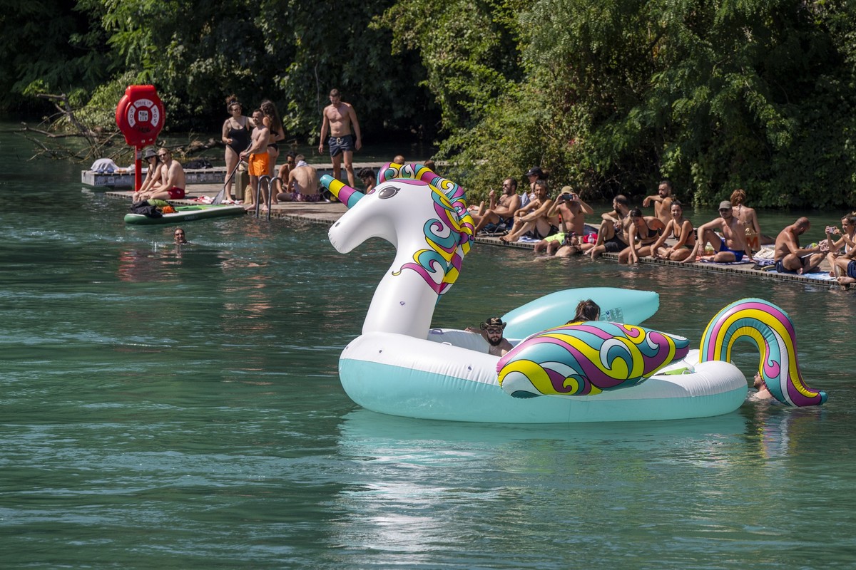 People in inflatable boats float down the Rhone river, in Geneva, Switzerland, Saturday, August 03, 2024. (KEYSTONE/Martial Trezzini)