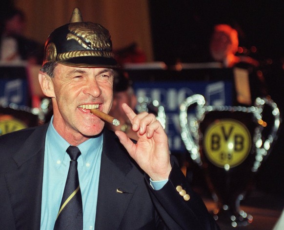 ARCHIV - 28.05.1997, Bayern, München: Damaliger Trainer von Borussia Dortmund, Ottmar Hitzfeld, raucht nach dem Sieg im Champions League Finale gegen Juventus Turin mit einer Pickelhaube auf dem Kopf  ...